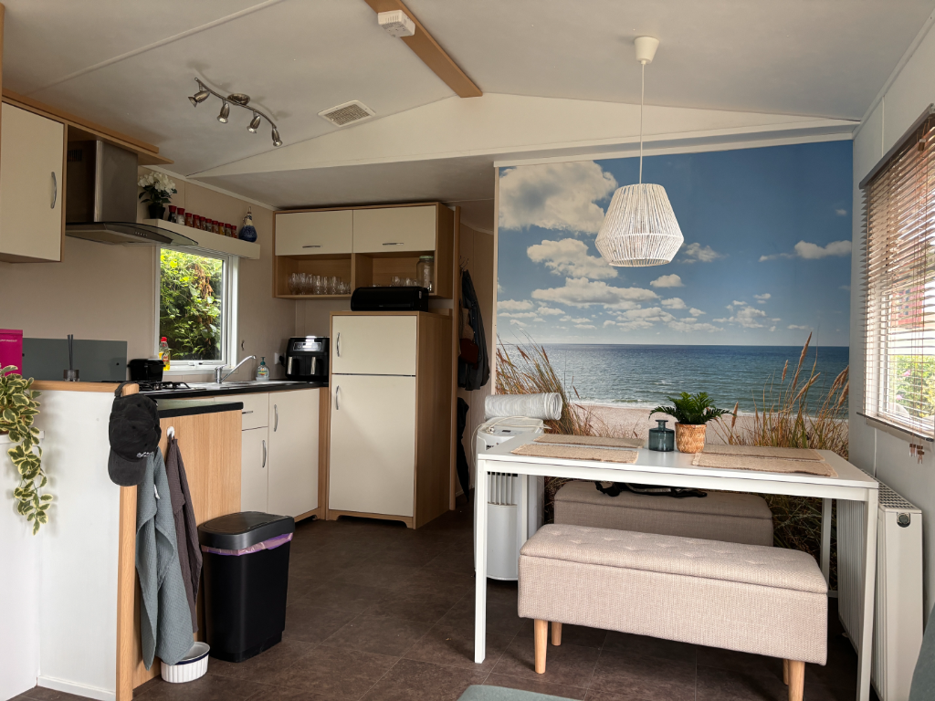 Eethoek en keuken in stacaravan met strand fotobehang en lichte meubels