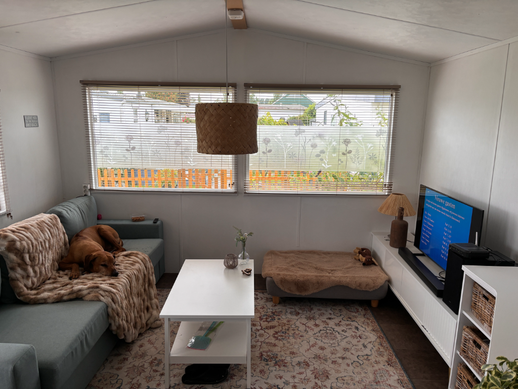 Nieuwe zithoek in stacaravan met slaapbank, wit tafeltje en licht interieur