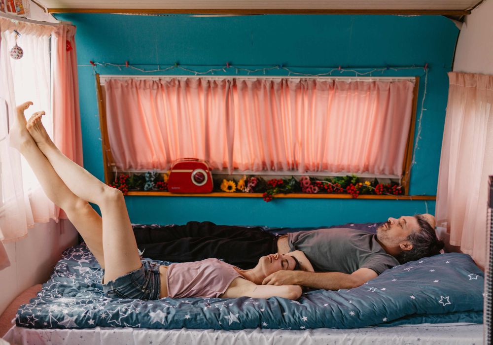 2 Kampeerders die op een dwarsbed in een caravan of camper liggen te relaxen